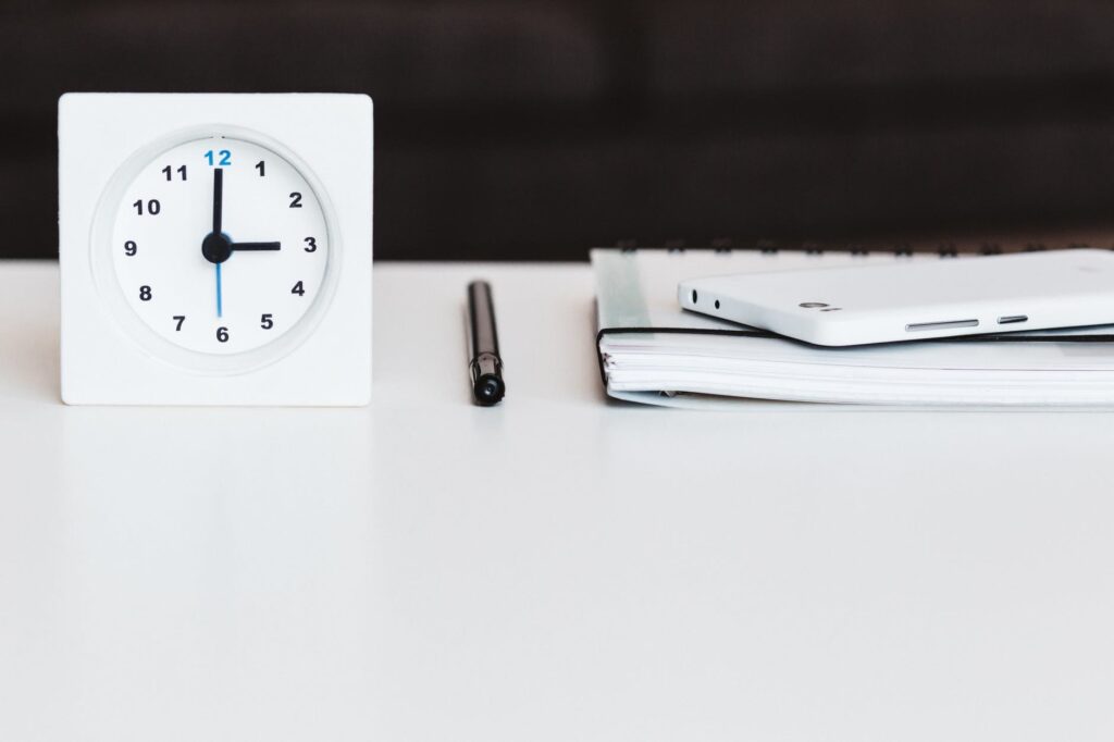 Incorporating Analytics in Timekeeping - clock on desktop with cell phone and notebook